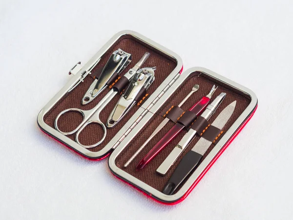 Набор необходимых инструментов для ухода за ногтями путешественника, включая ножницы, пинцет, пилу для ногтей и триммер в красном кожаном кармане — стоковое фото