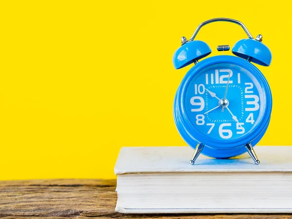 Çalar saat ve ahşap ve Sarı zemin üzerine beyaz kitap gibi ofis aksesuarları. Eğitim ve iş kavramı.