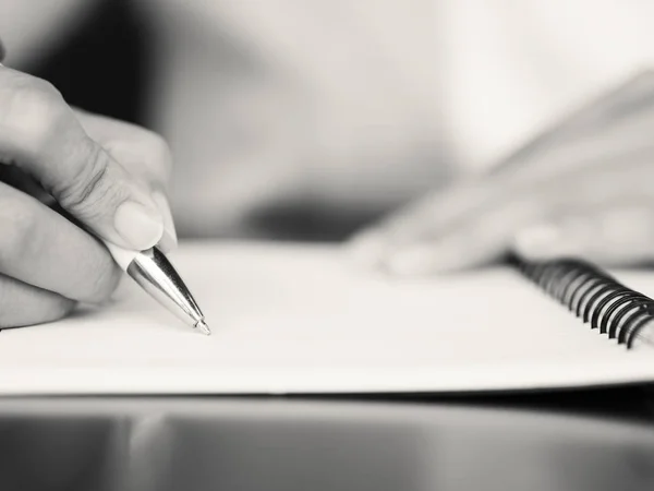 Zwart-wit vrouw hand schrijven met witte pen en Rekenmachine op de werktafel. Bedrijfsleven en het onderwijs concept. — Stockfoto