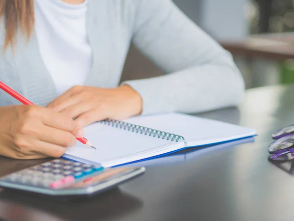 Närbild kvinna hand skriva med röd penna på arbetsbordet. Business och education koncept. — Stockfoto