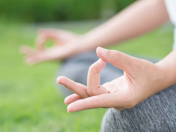 Dedo de yoga de mujer de primer plano que actúa sobre las manos en un fondo de enfoque suave con la naturaleza circundante. Concepto de estilo de vida saludable y relajación . — Foto de Stock