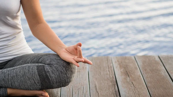 Dedo de yoga de mujer de primer plano que actúa sobre las manos en un fondo de enfoque suave con la naturaleza circundante. Concepto de estilo de vida saludable y relajación . — Foto de Stock