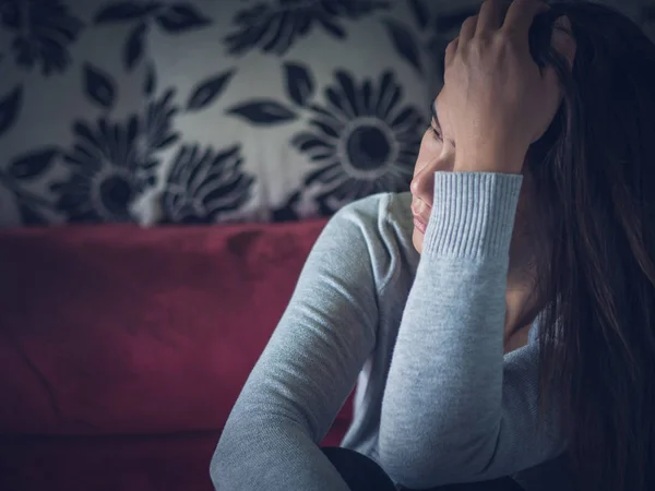 Closeup portrait of sad young woman sitting by sofa at home. — Stock Photo, Image