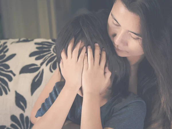 Närbild ledsen liten pojke som blir kramad av sin mor hemma. Föräldraskap, kärlek och samhörighet koncept. — Stockfoto