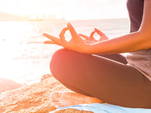 Yoga concept. Closeup vrouw hand beoefenen van lotus pose op het strand bij zonsondergang — Stockfoto