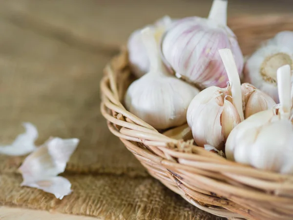 Closeup garlic clove, garlic bulb in wicker basket place on hemp sack background