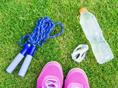Bir çift pembe spor ayakkabı ve su şişe yeşil çim ile