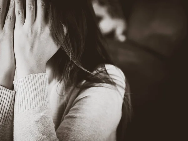 Portrait noir et blanc d'une jeune femme triste assise sur un canapé à la maison — Photo