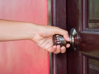 Tatlı kadın kahverengi ahşap kapı açıyor.