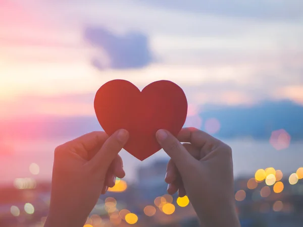 Soft focus hand holding beautiful heart during sunset background — Stock Photo, Image