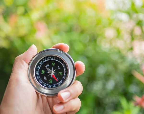 Closeup hand holding compass with  tree leaves bokeh  background — Stock Photo, Image