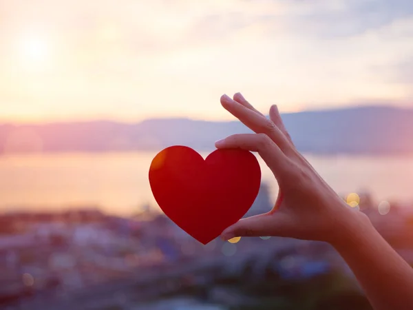 Sırasında günbatımı arka plan kırmızı kalp tutan Closeup el. Mutlu, aşk, Sevgililer günü fikir, işaret, sembol, kavram.