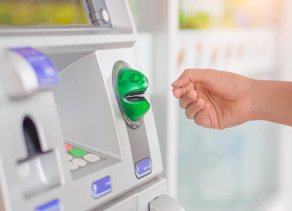 Крупный план женской руки, вставляющей дебетовую карту в банкомат — стоковое фото