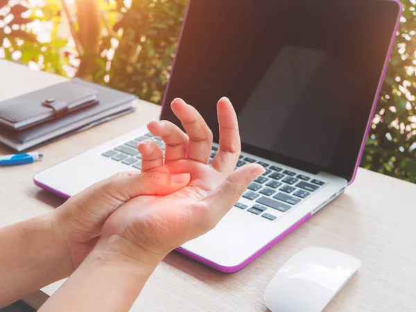 Närbild kvinna håller hennes smärtsamma hand använda dator. Office syndrom hand smärta av arbetssjukdom. — Stockfoto