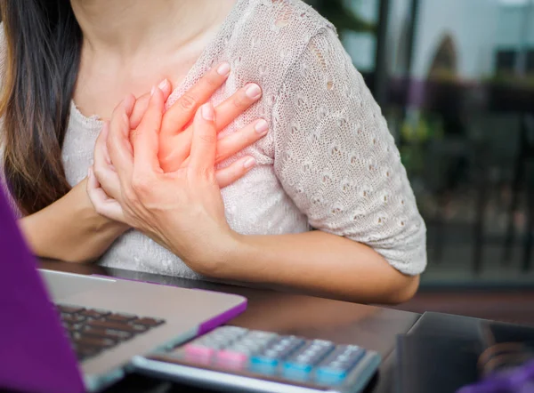 Nahaufnahme Frau mit Herzinfarkt. Frau berührt Brust und hat Brustschmerzen nach stundenlanger Arbeit am Computer. Bürosyndrom-Konzept. — Stockfoto