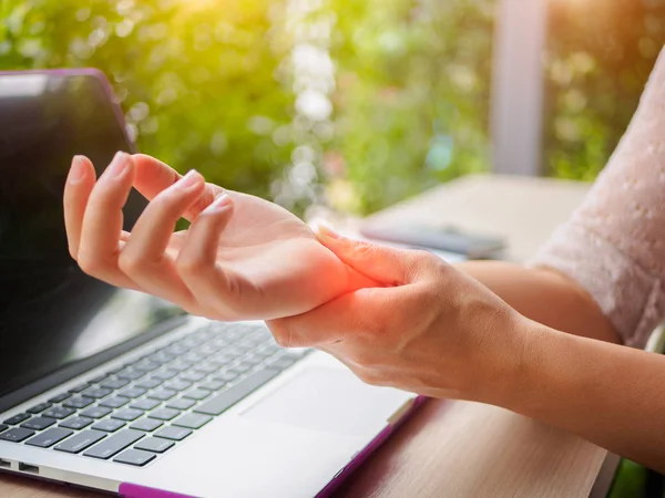 Närbild kvinna håller hennes smärtsamma hand använda dator. Office syndrom hand smärta av arbetssjukdom. — Stockfoto