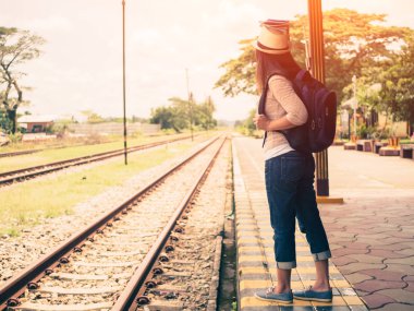 Retro tarzı Gezgin kadın yürüyüş ve beklediği tren demiryolu platformu. Tatil ve seyahat kavramı.
