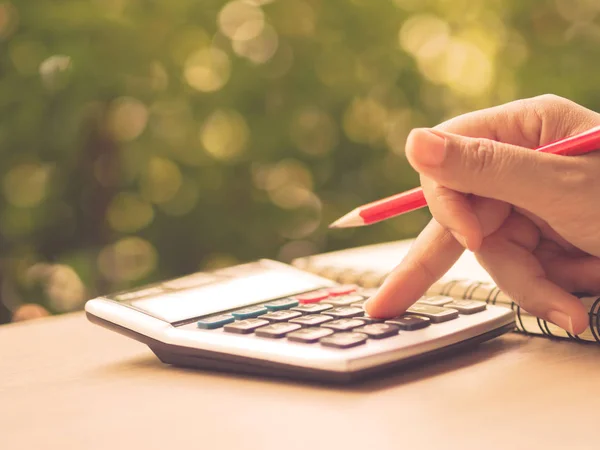 Mão mulher retro foco suave trabalhando com calculadora e segurando lápis vermelho com natureza verde folhas fundo . — Fotografia de Stock