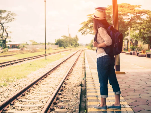 Retro tarzı Gezgin kadın yürüyüş ve beklediği tren demiryolu platformu. Tatil ve seyahat kavramı.