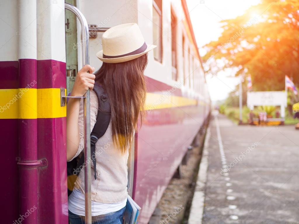 Closeup a beautiful woman with backpack on the steps of the passenger train. Travel and vacation concept.