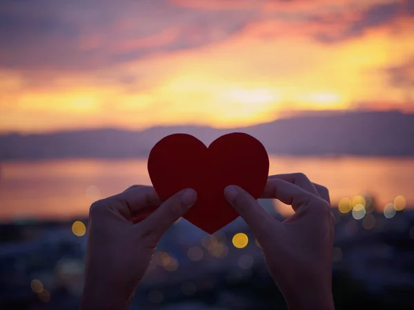 Silhouette Hand hält schönes Herz während des Sonnenuntergangs Hintergrund. glücklich, Liebe, Valentinstag Idee, Zeichen, Symbol, Konzept. — Stockfoto