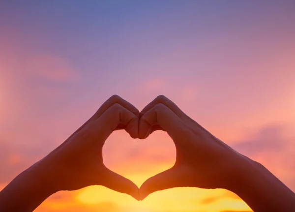 Siluet kadın kalp şekli günbatımı arka planda olmak eller