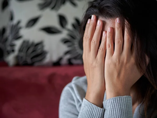 Closeup portrait of sad young woman sitting by sofa at home. — Stock Photo, Image