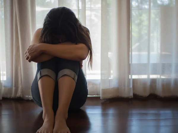 Wanita yang sedih dan putus asa memeluk lututnya dan menangis sambil duduk sendirian — Stok Foto