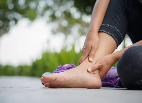 Молода жінка масажує свою болючу ногу від вправ — стокове фото