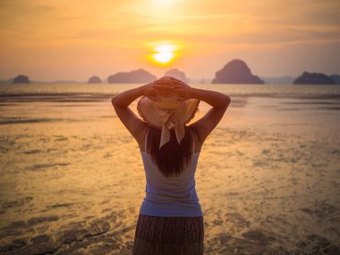 Kadın şapkası güneşin altında Kollarını açarak denize yakın