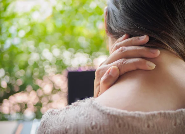 コンピューター上で長い時間作業した後、女性は痛みを感じている間彼女の首の後ろに手を置いた。オフィス症候群の概念. — ストック写真