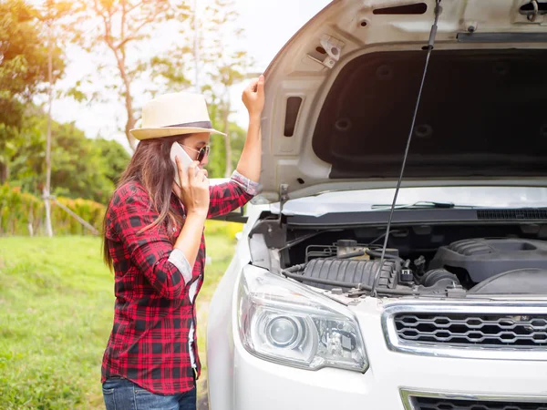 Kırık araba ile yolun kenarında duran genç kadın 