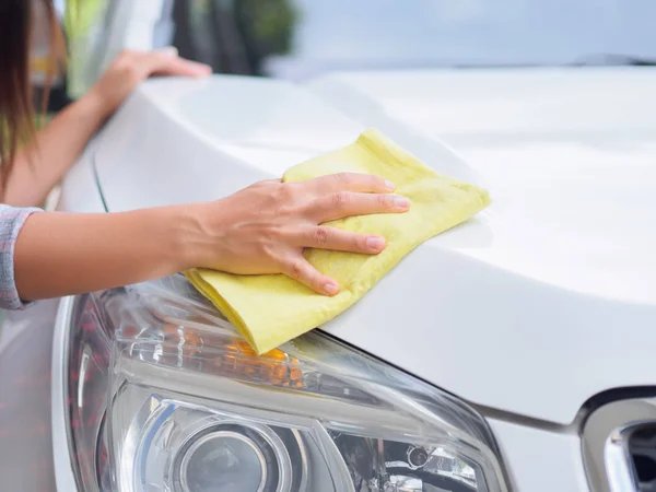 Mano con tela de microfibra amarilla limpieza coche blanco . — Foto de Stock