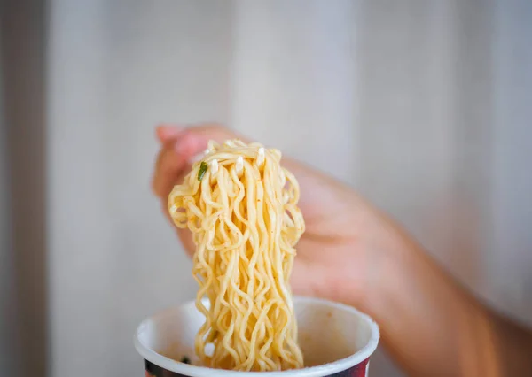 Baharatlı anlık erişte Kupası'nda yemek için çatal tutan el, 