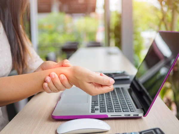 Closeup woman holding her wrist pain from using computer. — Stock Photo, Image