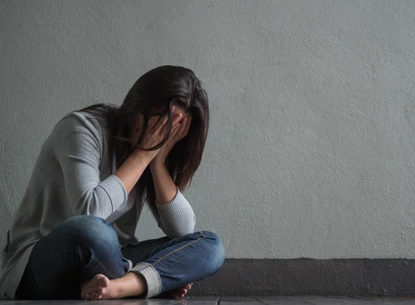 Mulher triste fechou o rosto e chorou sentada sozinha em uma sala vazia . — Fotografia de Stock