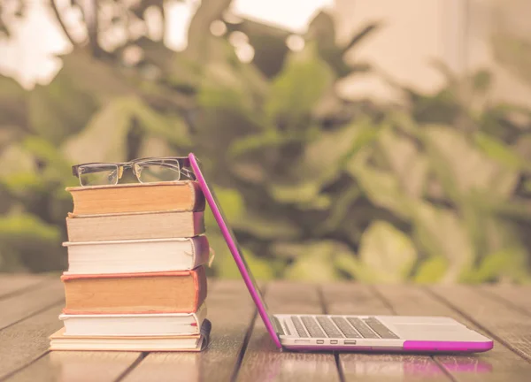 Vintage style, stack of books with laptop on wood table outdoor. — Stock Photo, Image