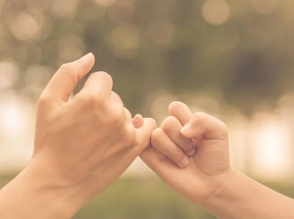 Retro mother holding a hand of her kid in spring day outdoors with green field background — Stock Photo, Image