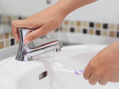 Kadın eller lavabo banyo, diş sağlığı bakımı diş macunu ile diş fırçası tutan.