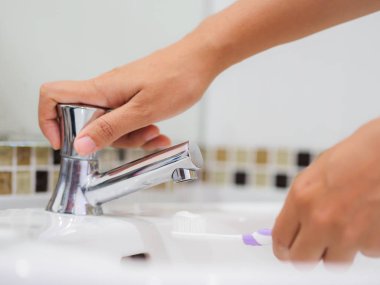 Seçici odak kadın el diş fırçası Diş macunu ile lavabo banyo, diş sağlığı bakımı tutuyor.