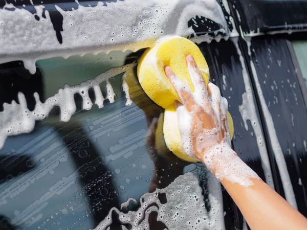 Mano de mujer con esponja amarilla lavado coche — Foto de Stock