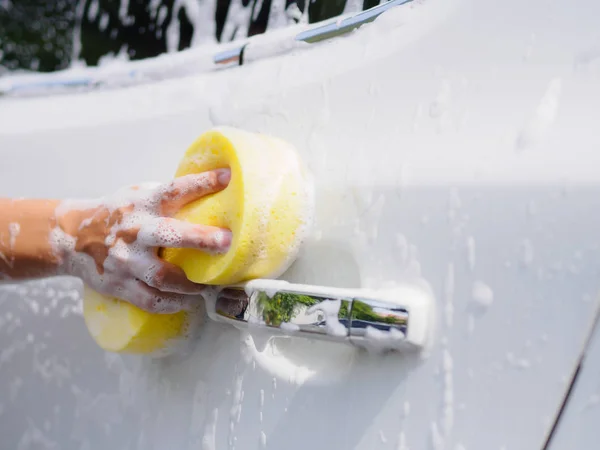 Mulher mão com esponja amarela lavagem carro — Fotografia de Stock