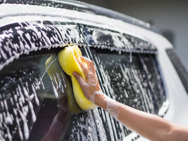 Mano de mujer con esponja amarilla lavado coche — Foto de Stock