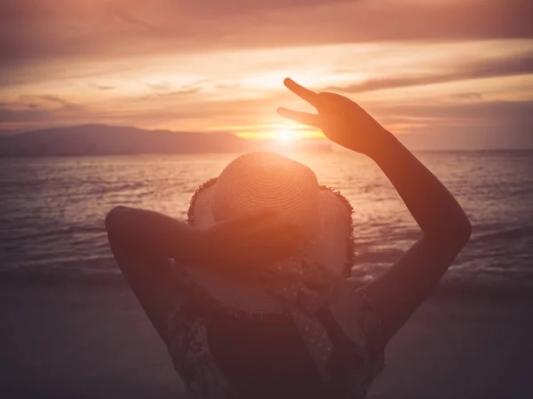 Силуэт женщина держит два пальца или знак победы на пляже — стоковое фото