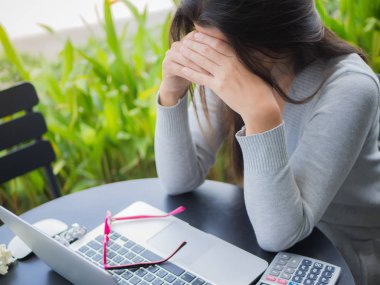 Genç Asyalı kadın baş ağrısı bir kafeterya bahçesinde otururken 