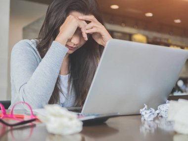 Genç Asyalı kadın baş ağrısı onu laptop ile bir kafede otururken