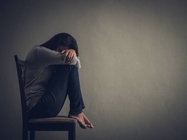 Depresif kadın evde karanlık odada bir sandalyede oturuyordu.