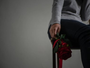 Oturma ve onun elinde kırmızı gül ile ağlayan üzgün kadın.
