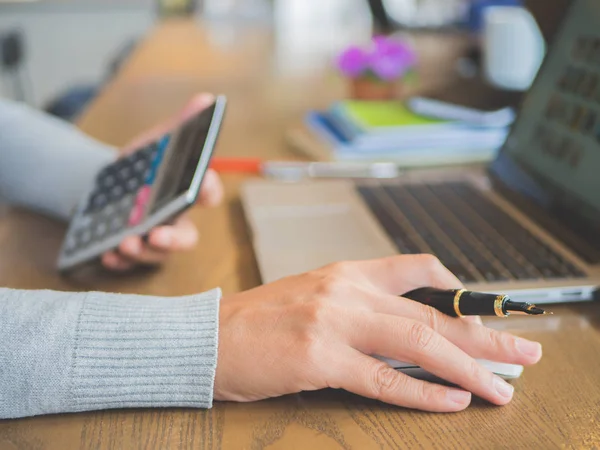 Closeup vrouw hand op haar laptop werken met Rekenmachine. — Stockfoto