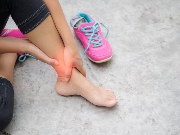 Woman suffering from an ankle injury while exercising.